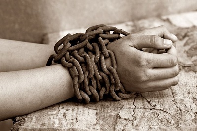 Photo of a woman’s hand tied together with a metal chain.
