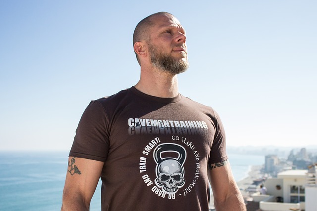 This is a close-up image of a man standing on top of a building with the sea behind him.