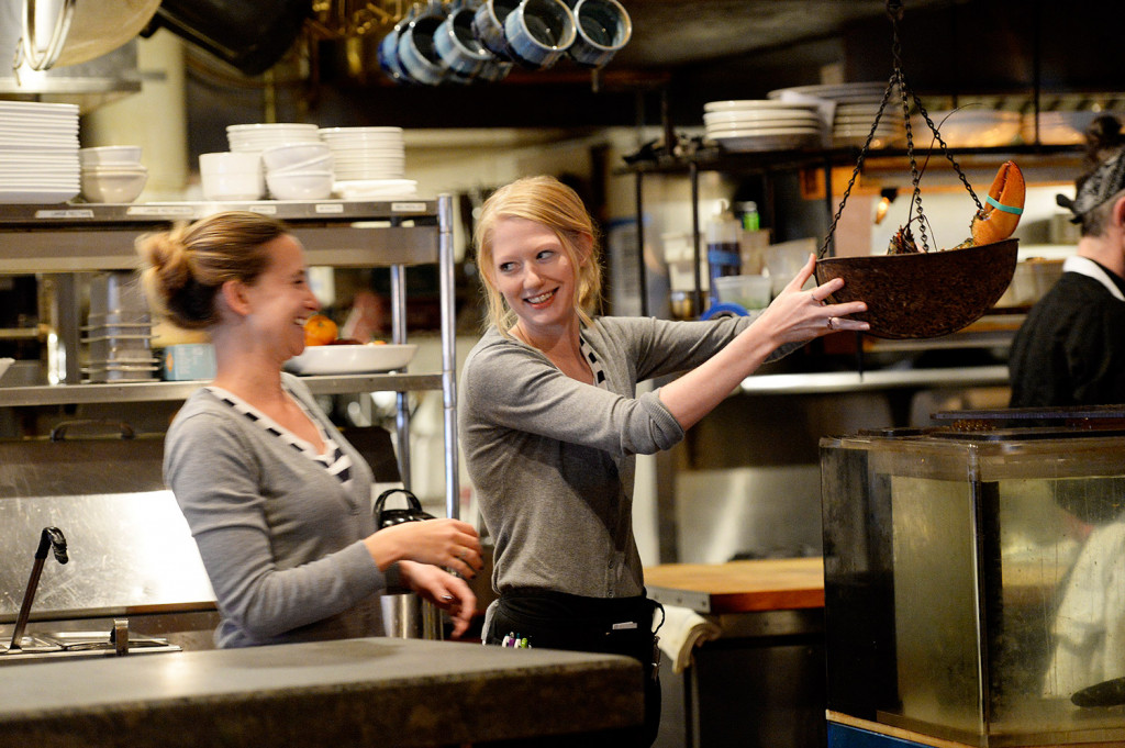 This is an image of two female servers having a conversation in a restaurant kitchen.