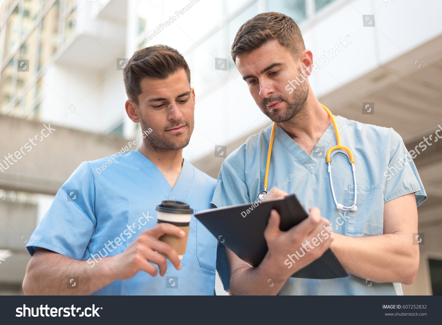 This is an image of two male nurses reviewing notes on a clipboard.