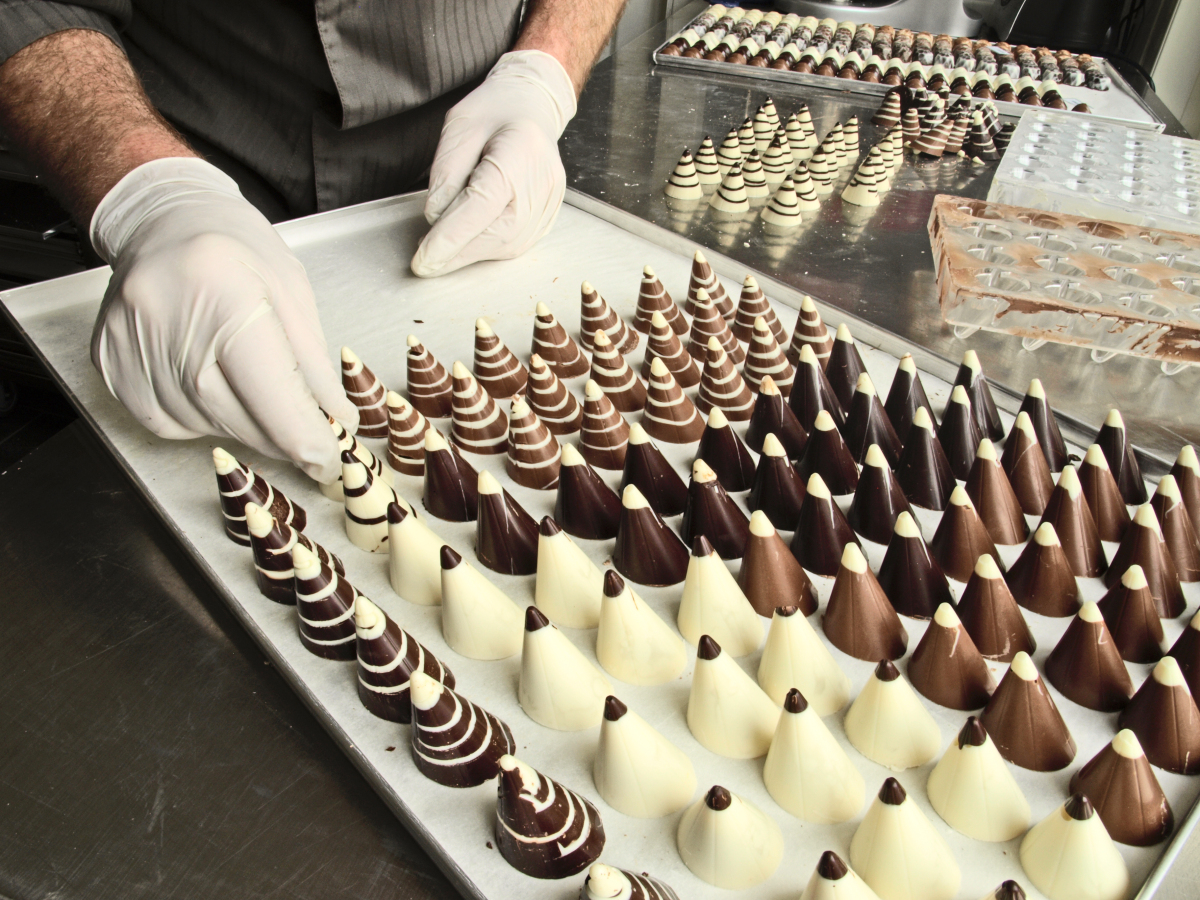 This is an image of an individual placing chocolates on a tray in a factory.