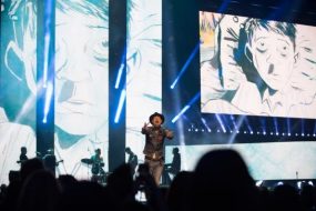 This is a photograph of Gord Downie performing at WE Day in Toronto on Wednesday, October 19, 2016. On the screen behind him 