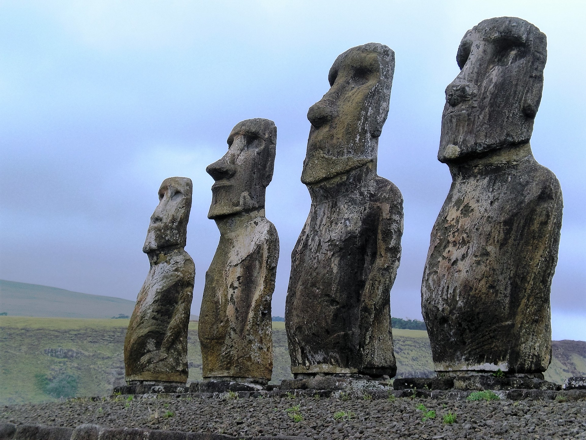 This is a photograph of a row of four large, stylized human statues carved out of stone.