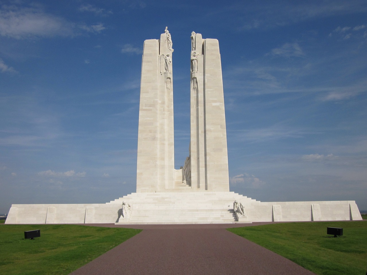 This is a photograph of a memorial made of white stone with two large towers in the centre.