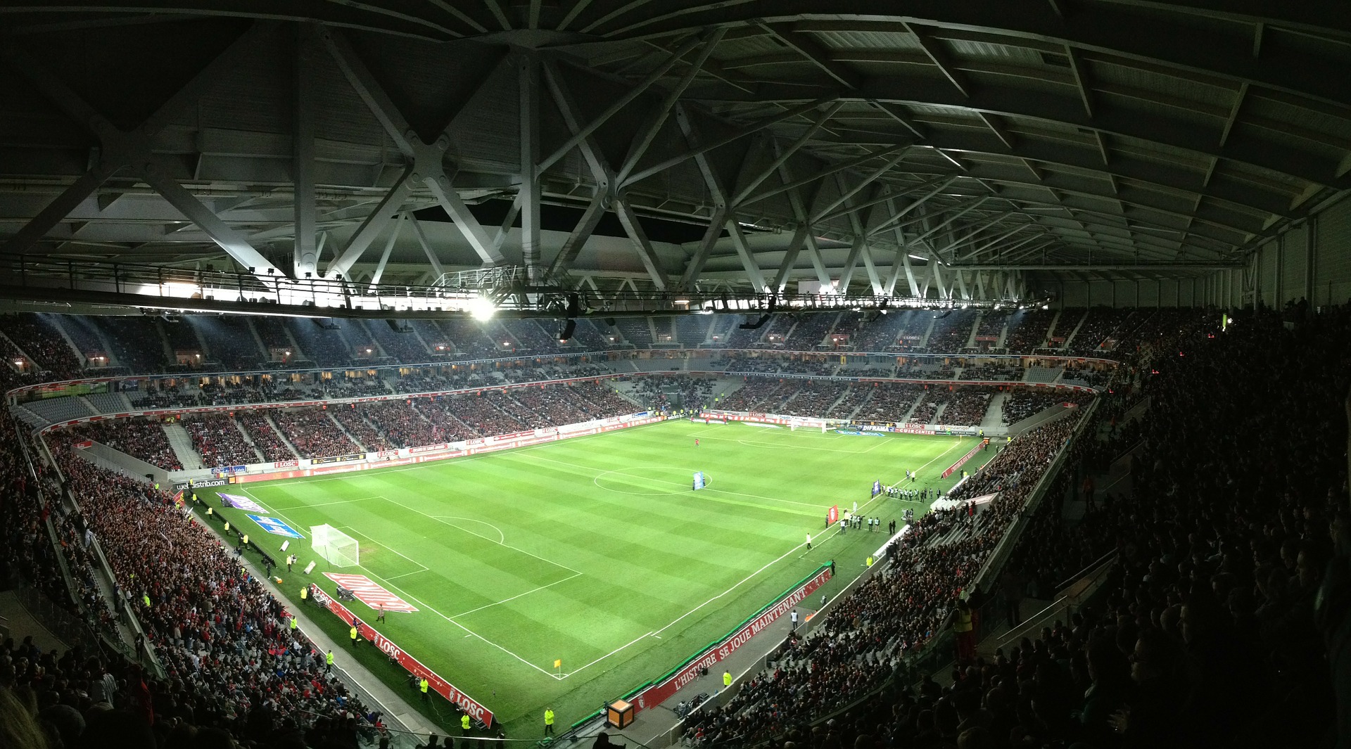 This is a photograph of a soccer stadium filled with fans and a game in progress under the bright lights.