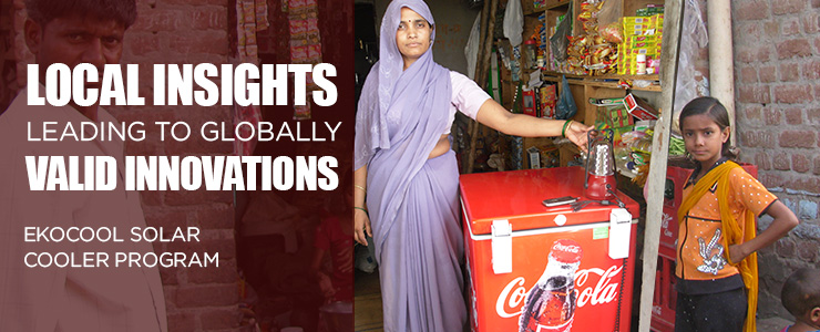 This photo is of an Indian woman standing beside a Coca Cola cooler with her left hand touching a lantern that is being charged at the charging station on the cooler. There is a little girl to the right of the cooler. The woman (and cooler) are in the front of a small kiosk type store. There is a man to the left of the photo that is faded into the background. The words &ldquo;LOCAL INSIGHTS LEADING TO GLOBALLY VALID INNOVATIONS, EKOCOOL SOLAR COOLER PROGRAM&rdquo; appear in front of the image of the man.