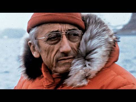 This is an image of Jacques Cousteau aboard a vessel with a waterway in background.