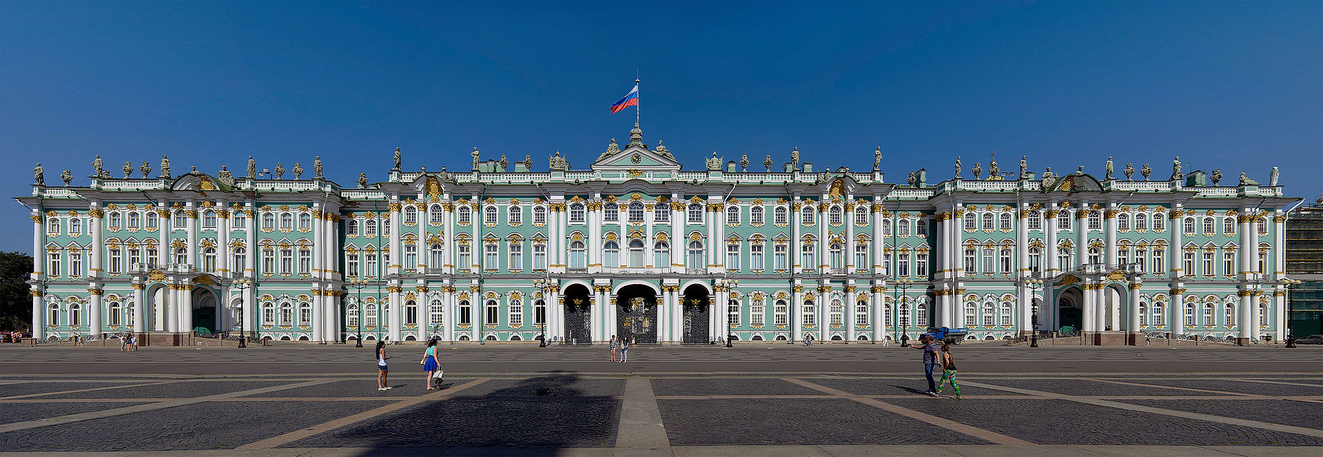 This is a photograph of the Winter Palace in St. Petersburg. It is made of green and white stone, is symmetrical and stable in appearance. Very similar in style to the palace at Versailles.