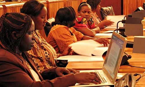 This is a photograph of 5 Rwandan women sitting in the Rwandan parliament. One of the women has a modern laptop computer. 
