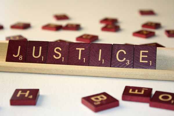 This is an image of a game of scrabble.  The letter pieces spell the word ‘Justice’.