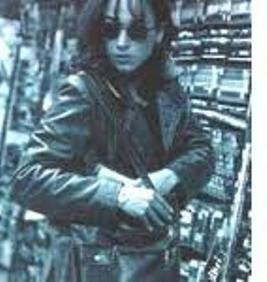 This is a black and white image of a woman in a shop. She is wearing sunglasses and she is placing something in her handbag. Her actions and facial expression make the viewer suspect that she is stealing.