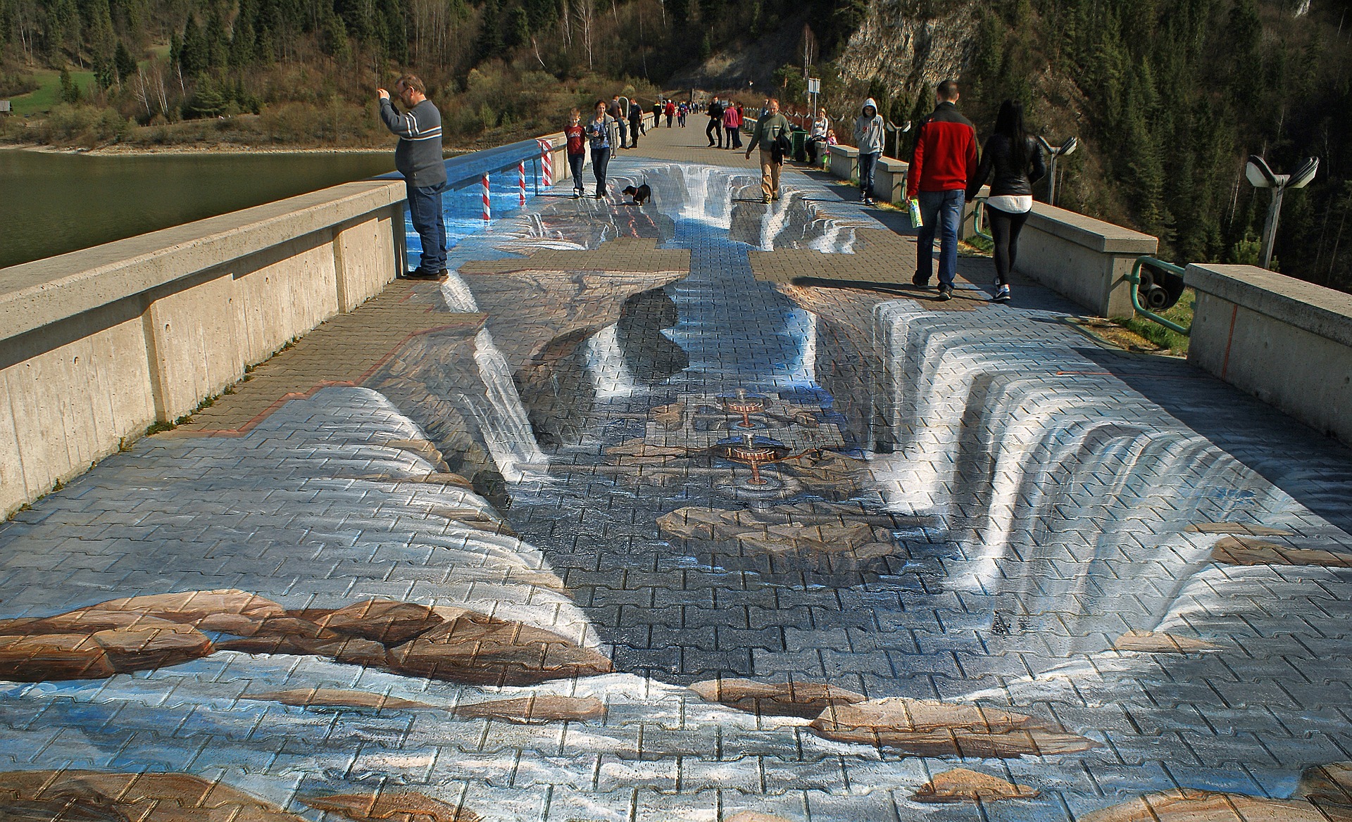 This is an image of a street that has been painted to look like there are waterfalls where the bricks should be.  People are taking photos as they walk.