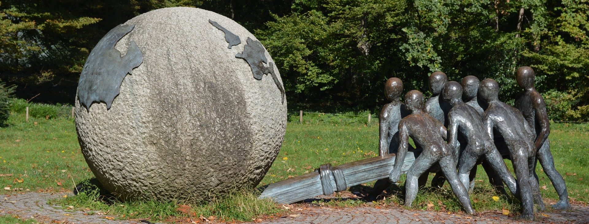 This is an image of a stone statue which portrays several people are working together using a lever to shift the world.