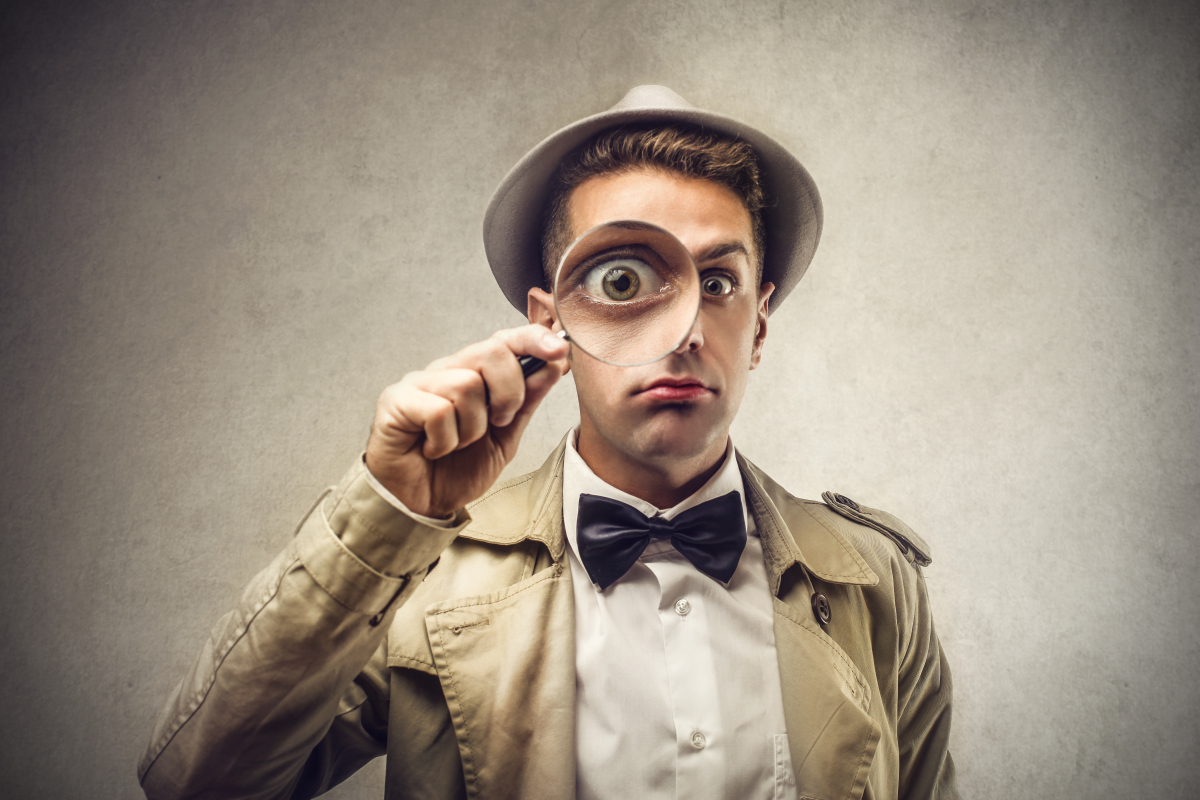 An image of a man holding up a magnifying glass.