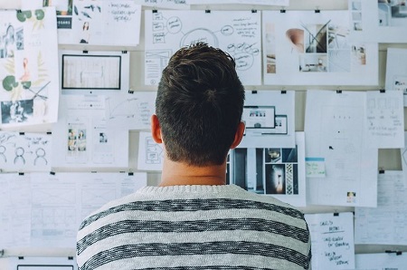An image of a game designer staring at storyboards and plans for a game.