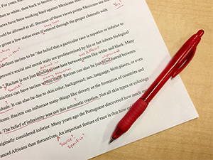 This is an image of a typed paper with a red pen placed on top of it; there are several corrections made on the paper in red ink.