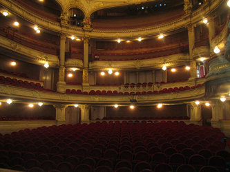 This is an image of rows of maroon and gold coloured velvet seats in a lavish old-fashioned opera house.