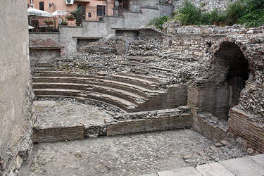 This is an image of an ancient amphitheatre with stone seating all around the stage.