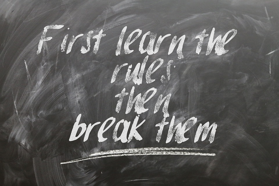 This is an image of a blackboard with the text &lsquo;First learn the rules then break them&rsquo; written on it.