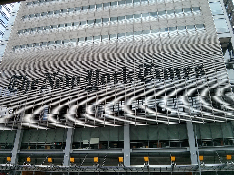 This is an image of the exterior of a glass-windowed building with &lsquo;The New York Times&rsquo; written across the front.