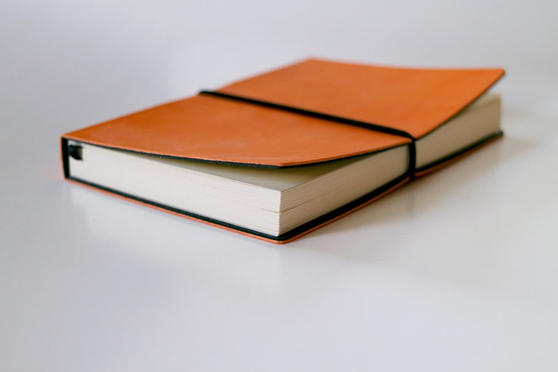 This is an image of a brown writing journal that is bound shut by an elastic.