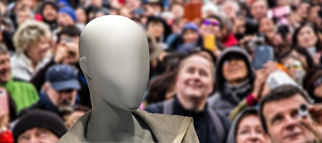 Une figure robotique apparait devant une foule d'etres humains.