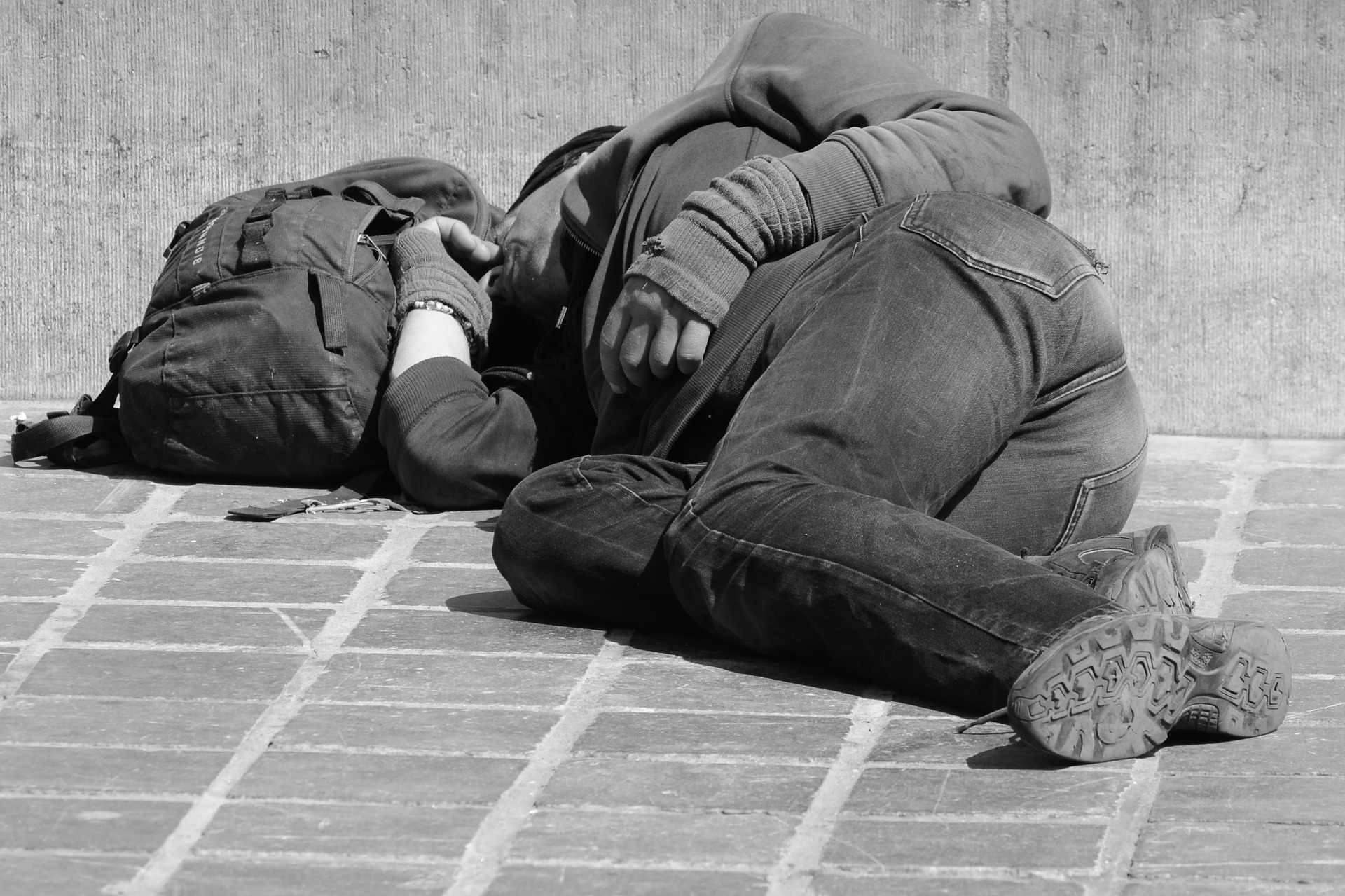 Un sans abri est couche sur le trottoir.