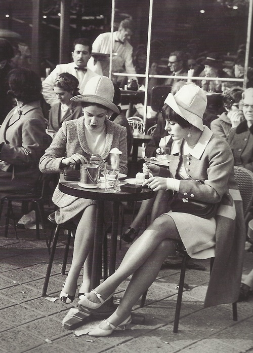 Deux dames prennent un cafe a une table exterieure d'un cafe a Paris.