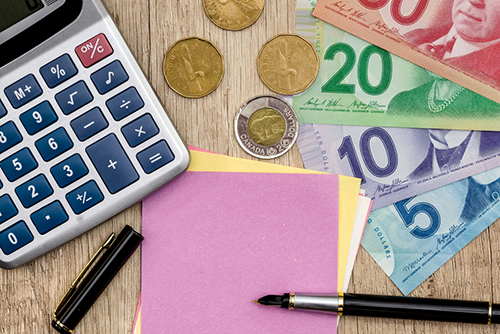 This is an image of Canadian currency beside a calculator and notepad.