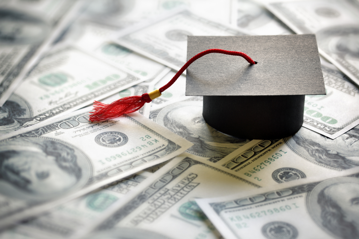 This graphic shows a graduation cap sitting on one hundred dollar bills.