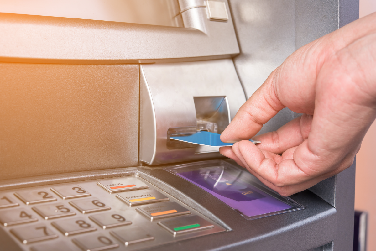 This graphic shows a hand inserting a debit card into a bank machine.