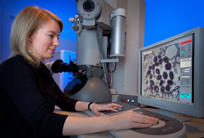 This is an image of a woman working a piece of lab equipment.