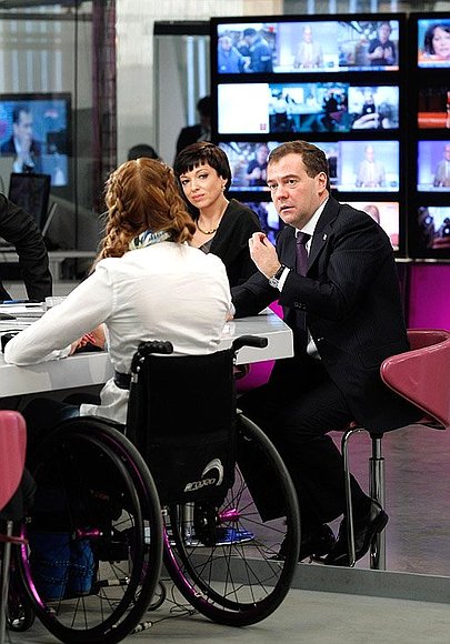 This is an image of two women (one of whom is in a wheelchair) and a man participating in a meeting in a newsroom.