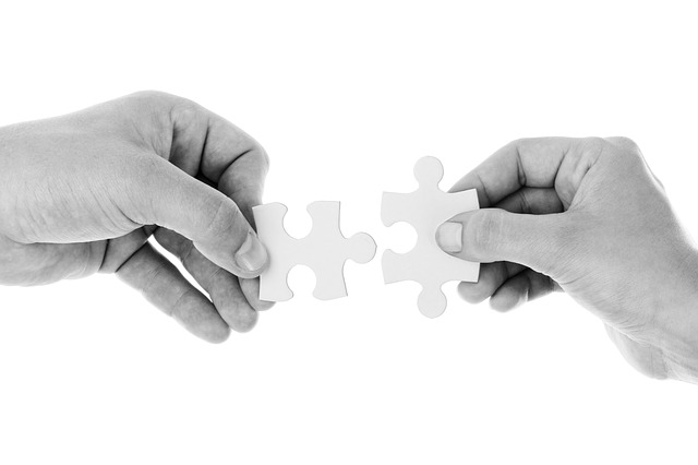 This is a photograph of two hands putting together two puzzles pieces.