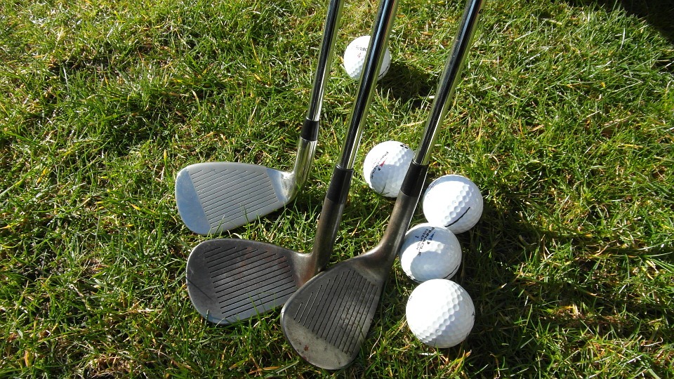 This is an image of 5 golf balls and 3 golf clubs.