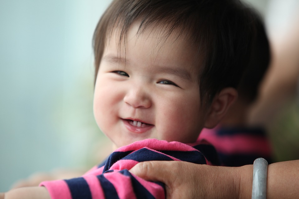 This image shows a young one-year-old toddler grinning at the camera. 