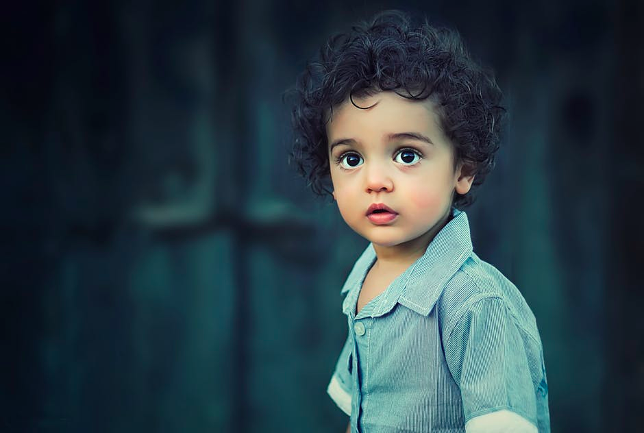 This image shows a two-year-old child standing in a walled garden. 