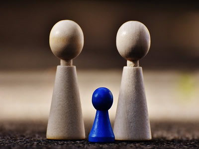 This is an image of two wooden game pieces of the same size, with a smaller blue game piece between them.