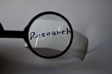 This is a photograph of a piece of tape with the word research on it being looked at through a magnifying glass.