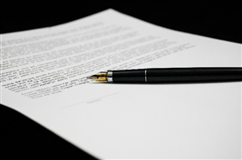 This is a photograph of a pen sitting on a white sheet of paper which has words and a signature line on it.
