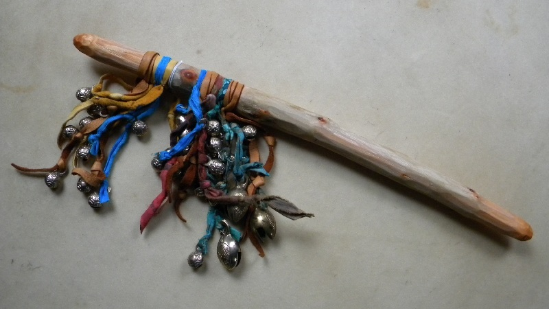 This is an image of a stick adorned or decorated with leather ties and bells.