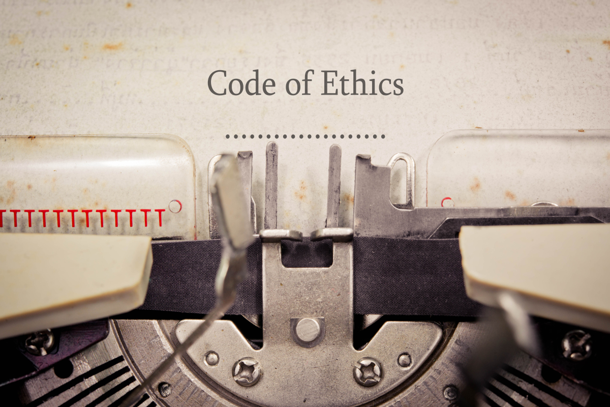 This image is a photograph of an old-fashioned type writer.  There is a piece of paper in the typewriter.  The words Code of Ethics is typed on the page.