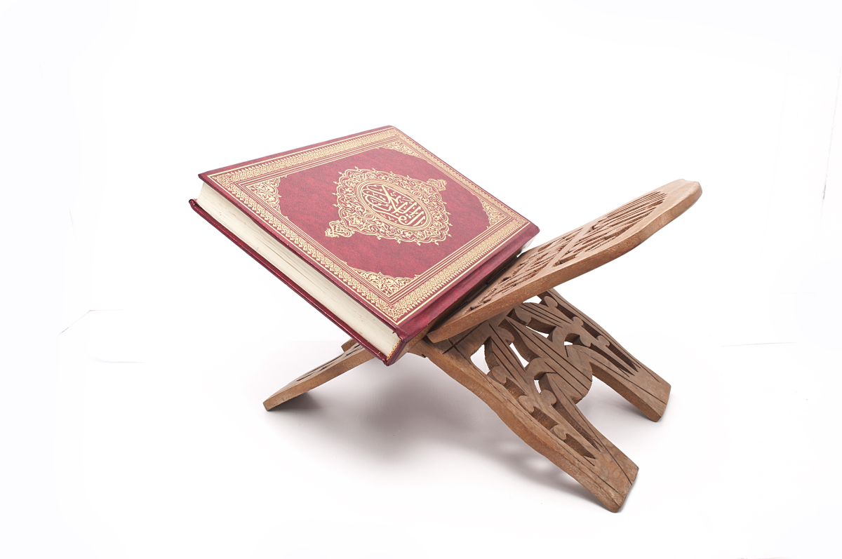 This is an image of the holy Quran on a wooden book stand.