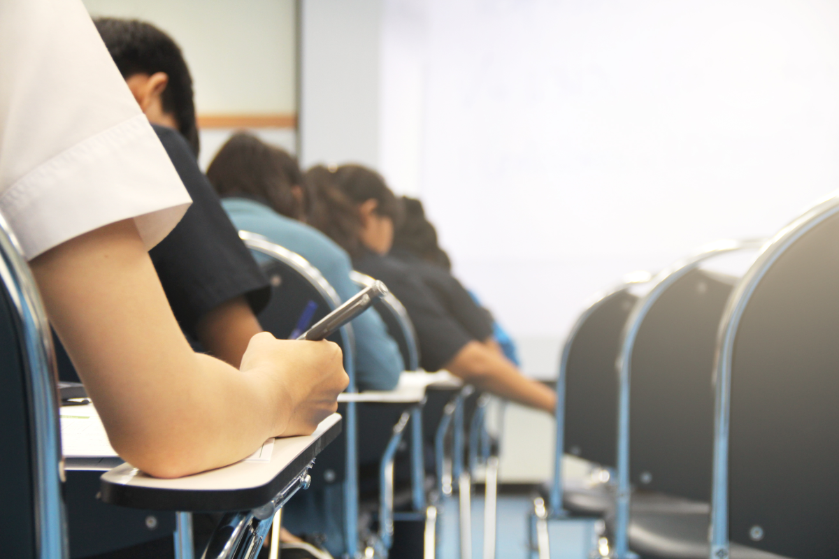 This is an image of students sitting in rows of desks and writing exams.