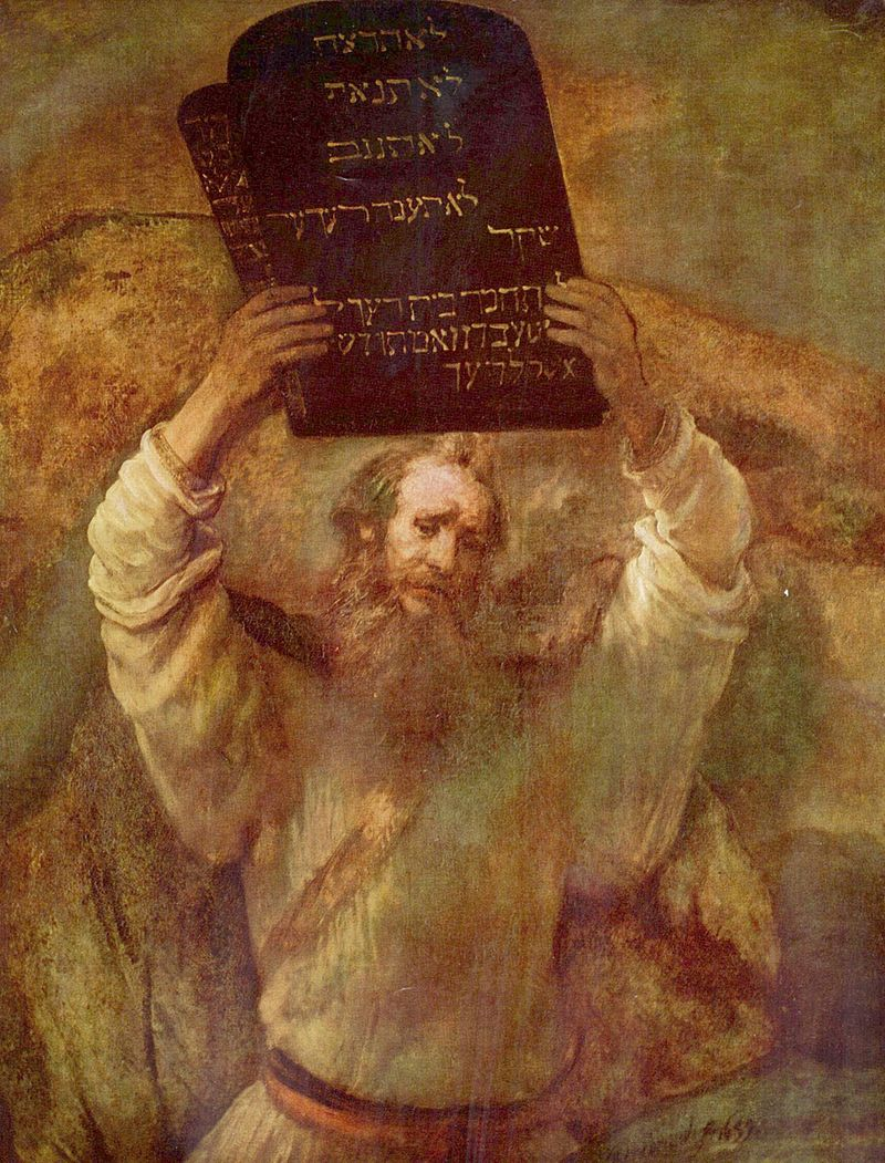 This is an image of Moses as depicted by the painter, Rembrandt, holding aloft two stone slabs that have the Ten Commandments written on them.