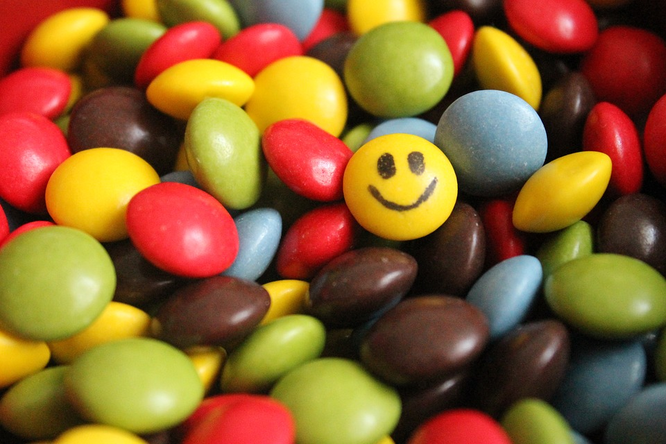 This is an image of a pile of candy, one of which has a smile painted on it.