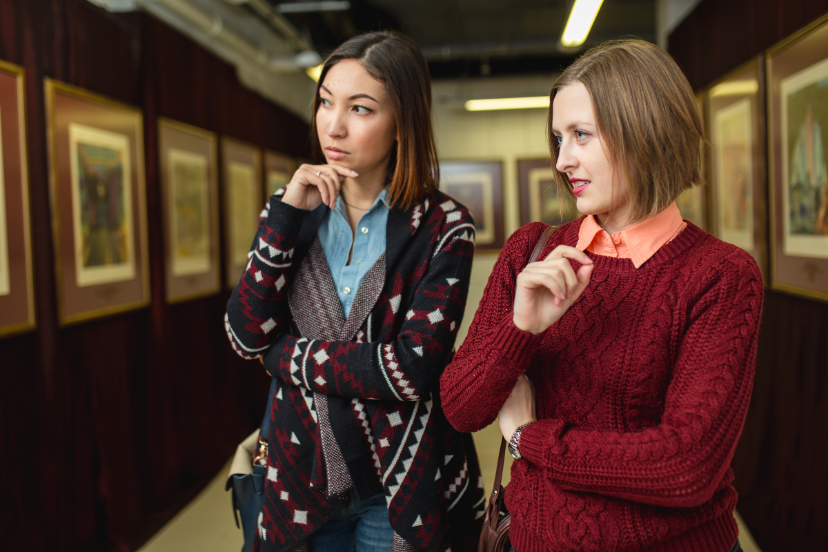 This is an image of two women who are judging artworks in a gallery.
