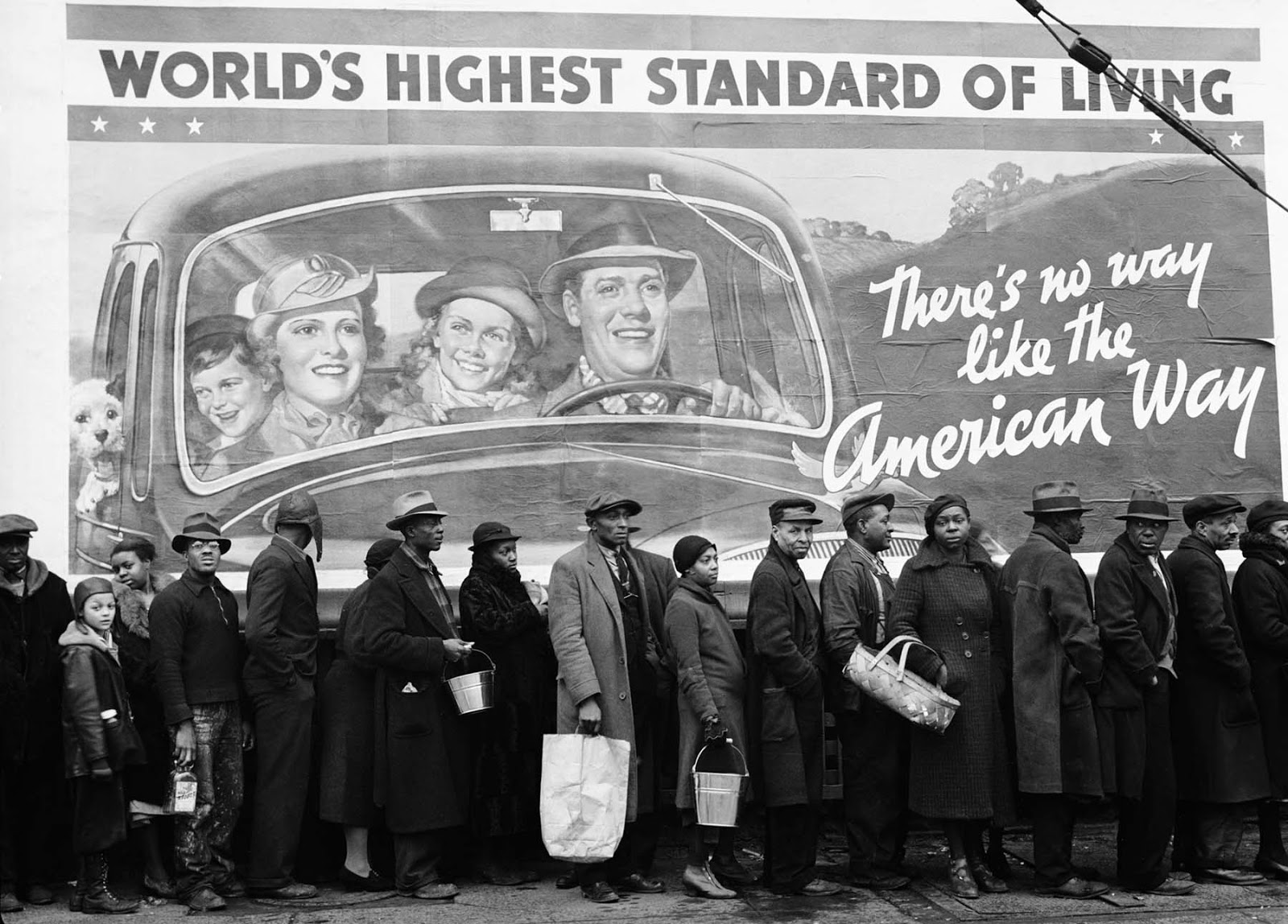 This is an image of 1937 African American flood victims lined up in front of a billboard that features well-dressed white Americans driving in a car and declaring that America has the ‘world’s highest standard of living.’