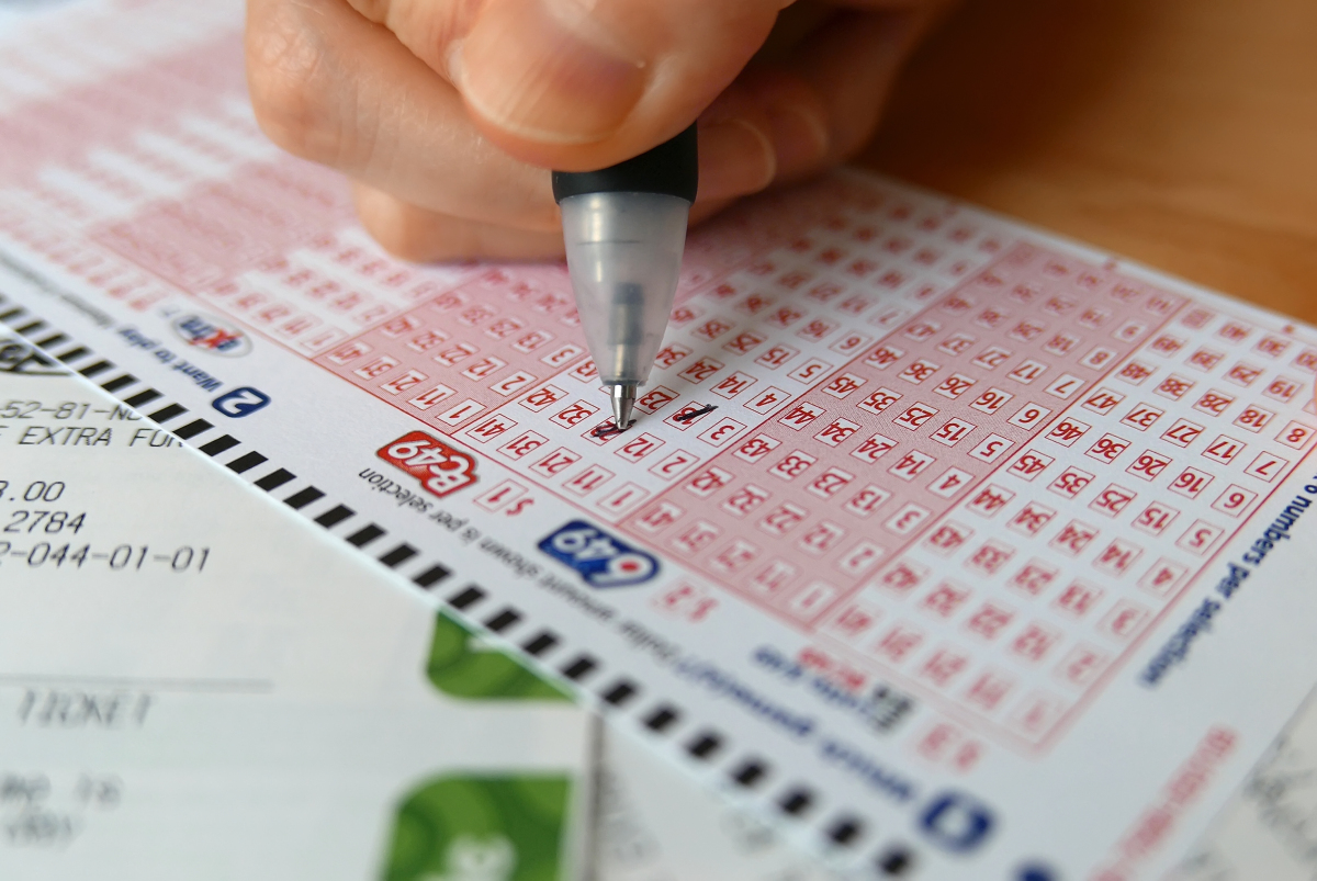 This is an image of a close-up hand marking number on a 649 lottery ticket.