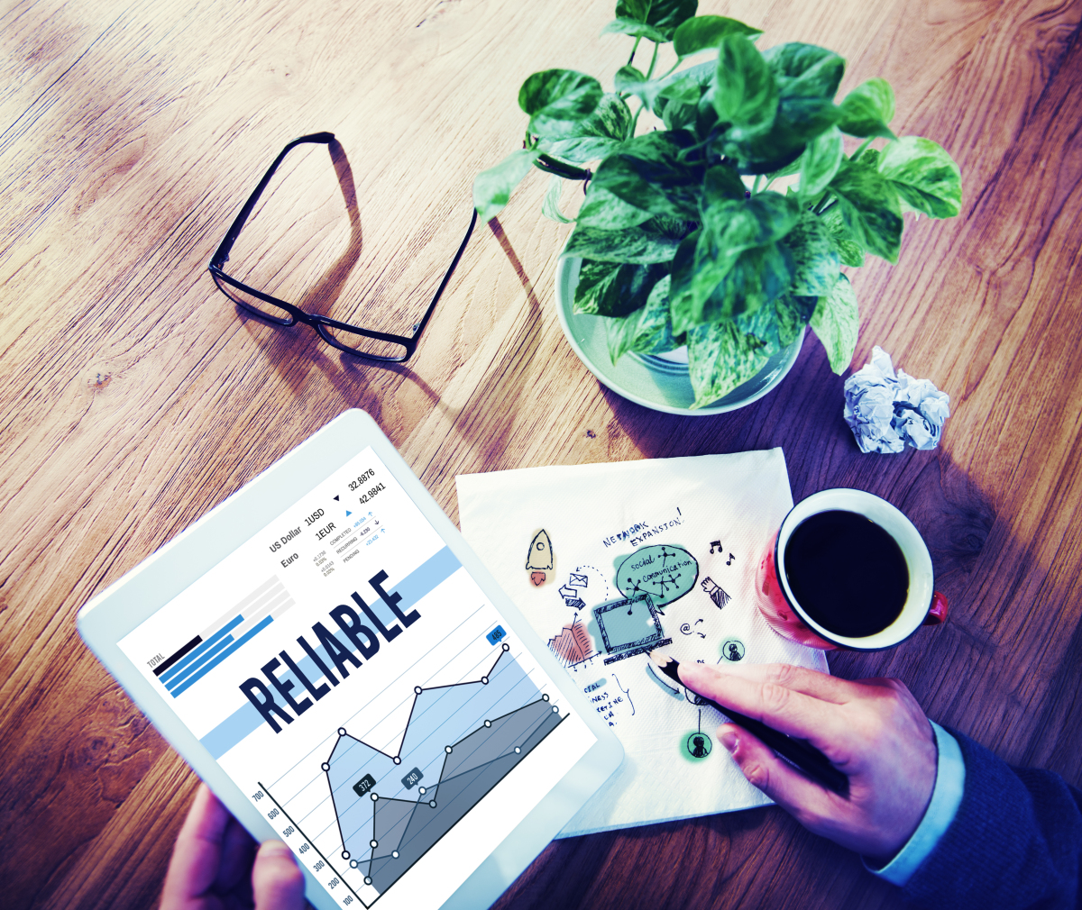 This is an image of a person reviewing reports with a coffee and the word 'reliable' is on the report.